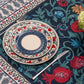 Corner view of the BlueTabla Georgian Alphabet & Pomegranate blue tablecloth with a place setting and floral centrepiece.