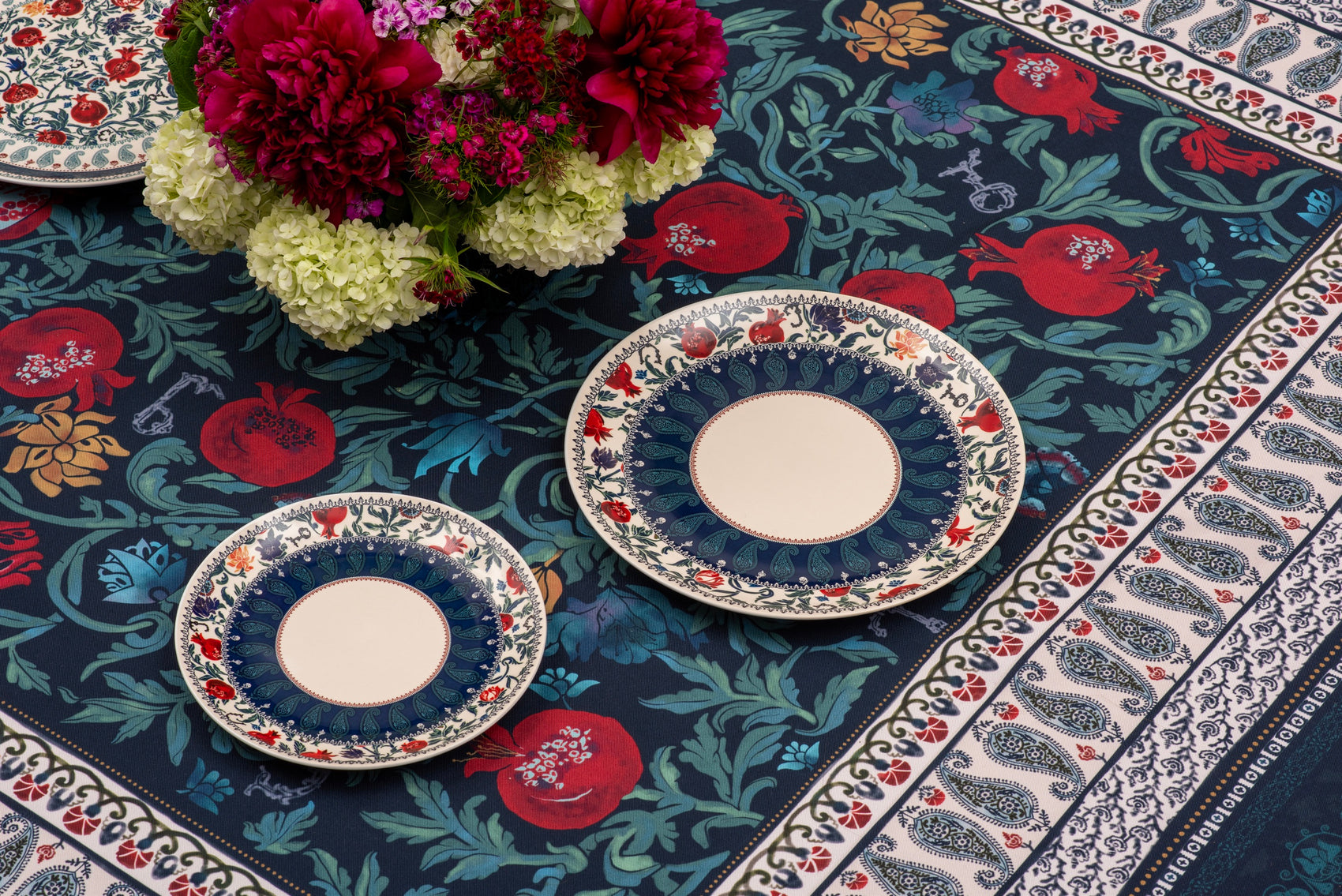 Detail of the BlueTabla Georgian Alphabet & Pomegranate tablecloth, showing the pomegranate-vine field and paisley border.