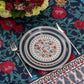 Place setting on the BlueTabla blue pomegranate tablecloth with cutlery, a peony bouquet and the paisley border in view.