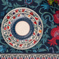 Stacked patterned plates on the BlueTabla blue tablecloth, showing the pomegranate and Georgian alphabet motif in detail.