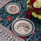 Two patterned place settings on the BlueTabla blue pomegranate tablecloth, with paisley border and hydrangea bouquet.